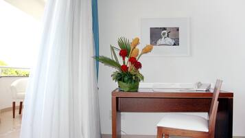 A room with a wooden desk, a chair, a telephone, and a framed picture on the wall.