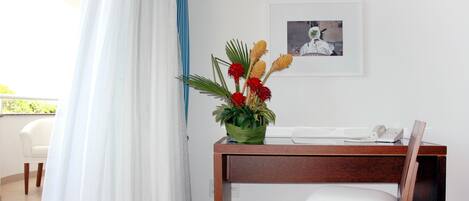 A room with a wooden desk, a chair, a telephone, and a framed picture on the wall.