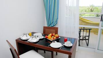 A dining table set with plates, cutlery, and a fruit bowl.