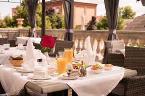An outdoor dining area with tables set for breakfast, including bread, eggs, and fruit. - Schlosshotel Zum Markgrafen (Quedlinburg)