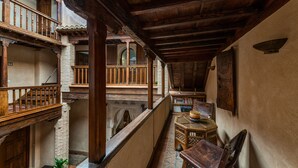 A traditional interior with wooden balconies, a stone staircase, and a small wooden table with chairs. - Casa Morisca Hotel Boutique (Granada)