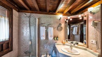 A bathroom with a glass-enclosed shower, a sink, and a large mirror.