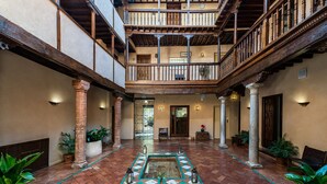 A spacious courtyard with a tiled floor, columns, and potted plants. - Casa Morisca Hotel Boutique (Granada)