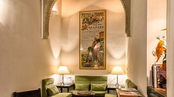 Una habitación acogedora con un sofá verde, dos mesitas de noche con lámparas, una mesa de centro de madera con flores, un arco decorativo y un cartel en la pared.