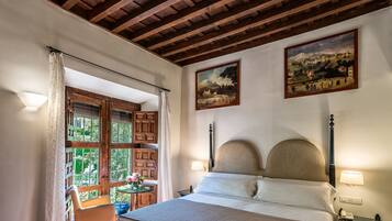Ein Schlafzimmer mit Holzboden, einem Bett mit Kopfteil, zwei Wandlampen und einem Fenster mit Vorhängen.