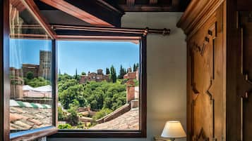 Una habitación con un ventanal que ofrece vistas a un pueblo histórico con edificios y árboles.