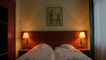 A hotel room with two beds, each with a nightstand, a lamp, and a framed picture on the wall.