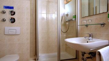 A bathroom with a glass-enclosed shower, a white sink, and a toilet.