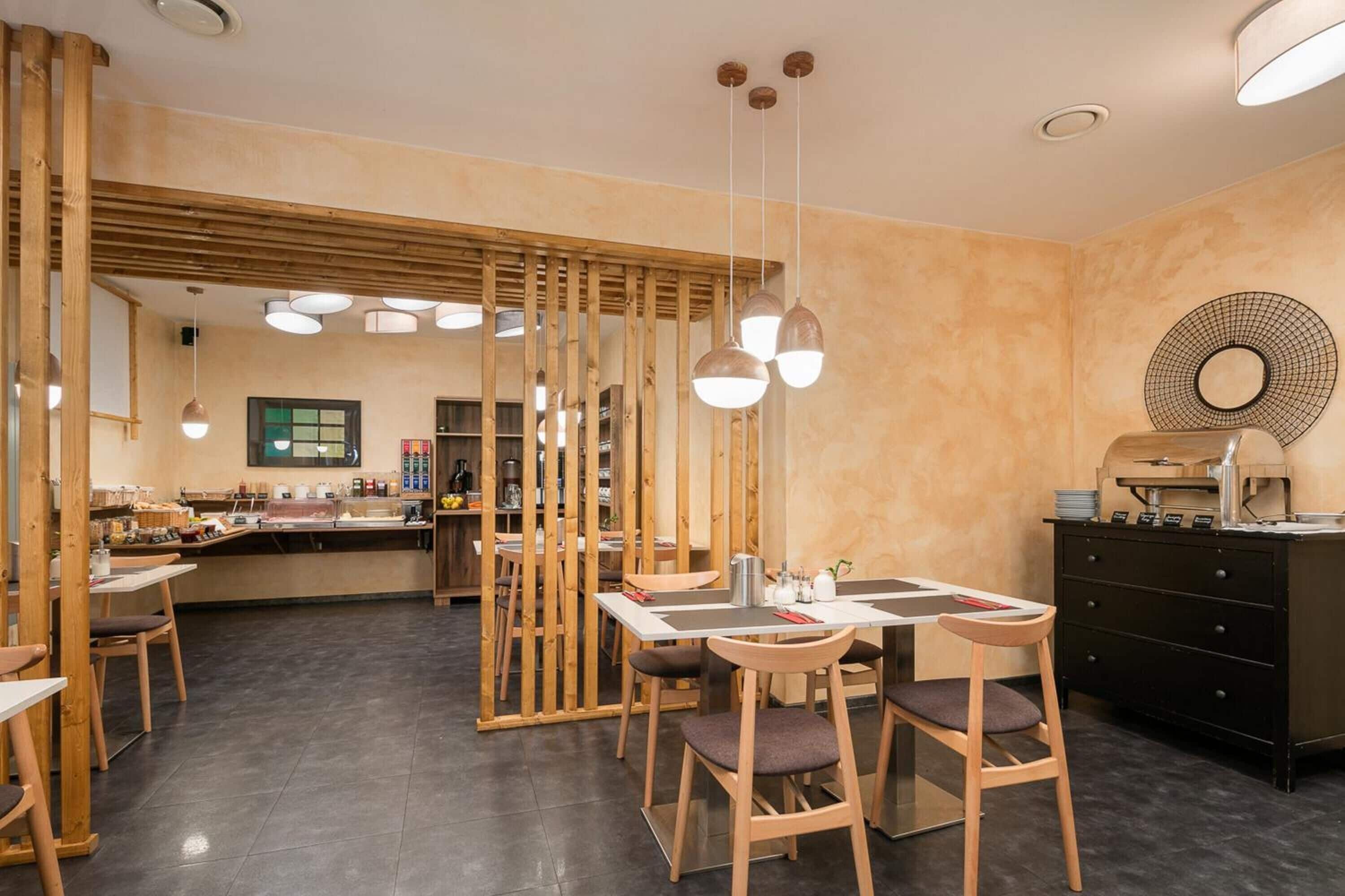 A modern restaurant with wooden furniture, pendant lighting, and a central dining area.