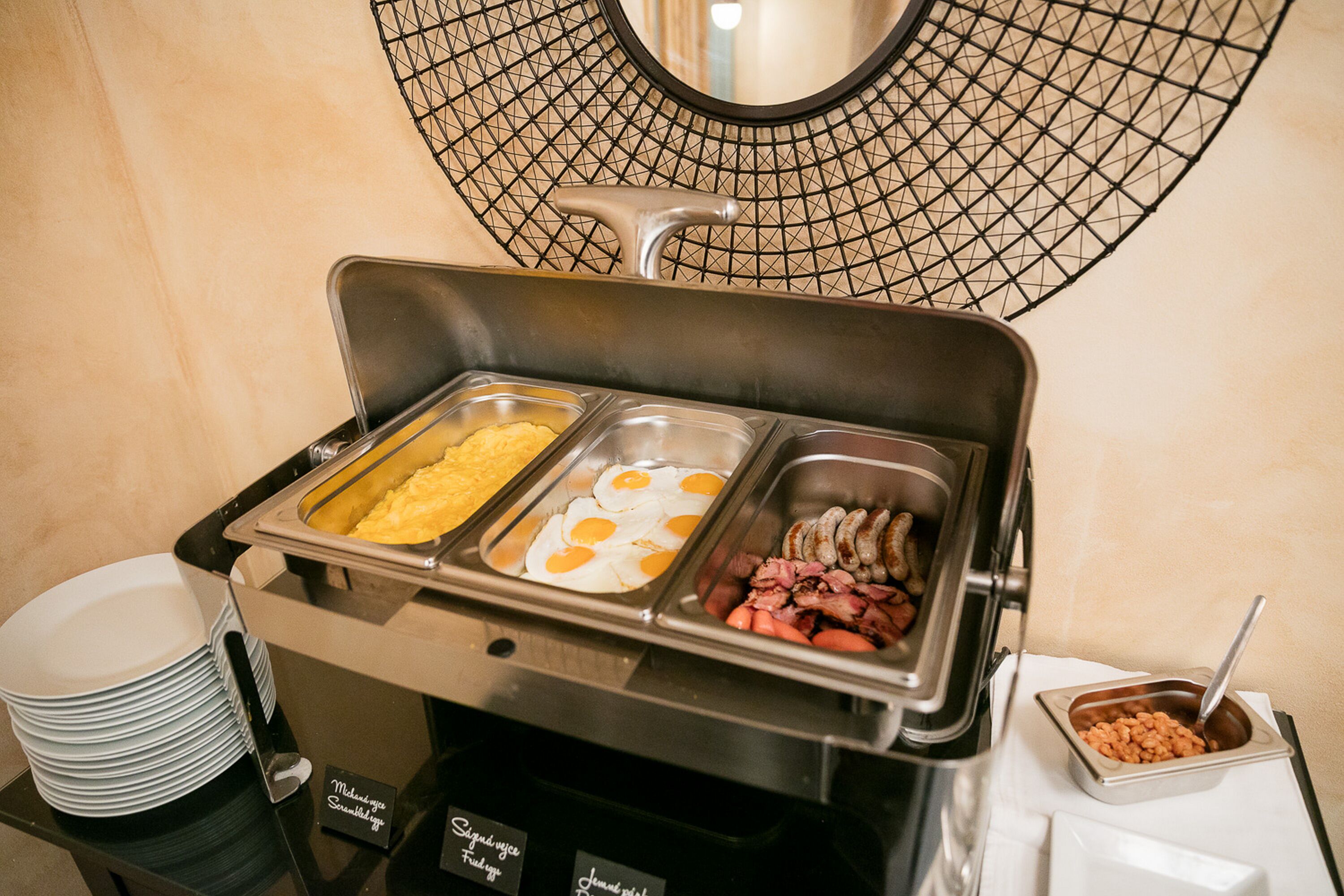 A buffet with various food options including eggs, sausages, and meat.