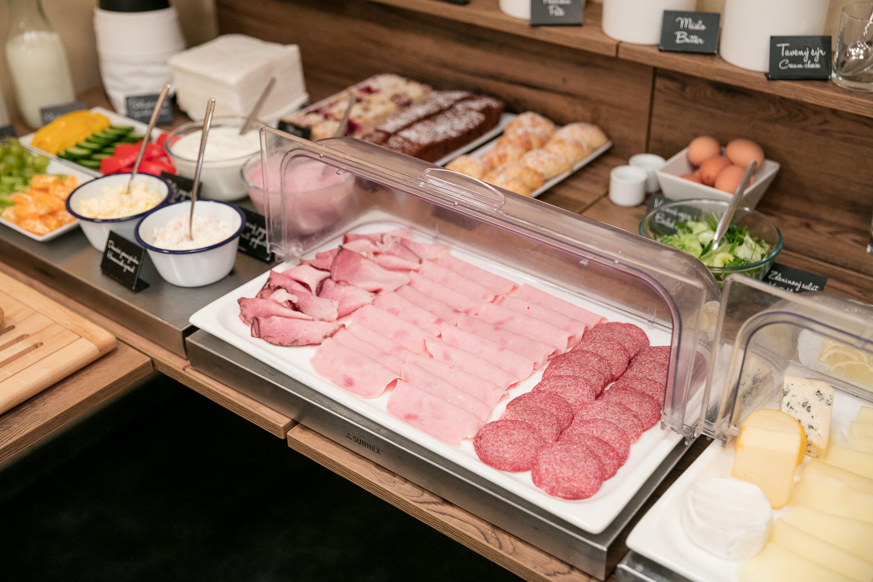 A buffet with various food items including sliced meats, cheeses, and salads.