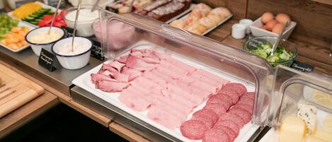 A buffet with various food items including sliced meats, cheeses, and salads.