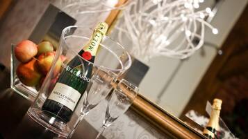 A bottle of Moët & Chandon champagne in a glass, with a bowl of fruit and a framed picture in the background.