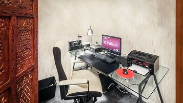 A modern office with a glass desk, a computer, a printer, and a chair.