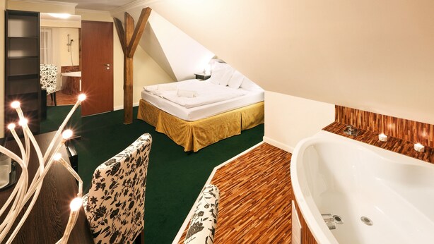 Un dormitorio con cama, suelo de madera, bañera y una silla.