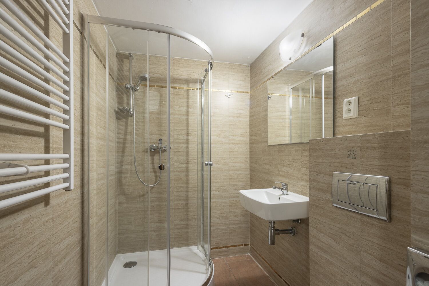 Un bagno moderno con doccia a vetro, lavandino bianco e porta asciugamani.