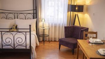 Un dormitorio con una cama, una silla, una mesita y una lámpara.