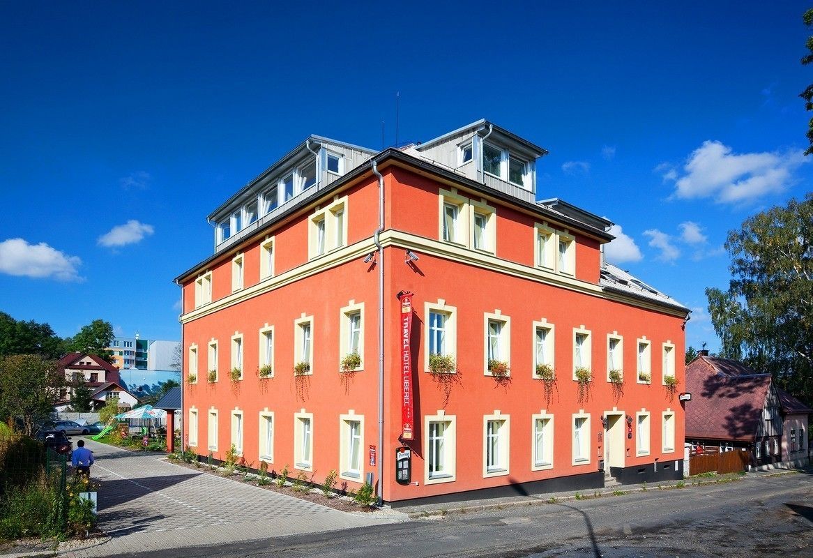 En rød bygning med mange vinduer og en balkon, sandsynligvis et hotel eller pensionat.