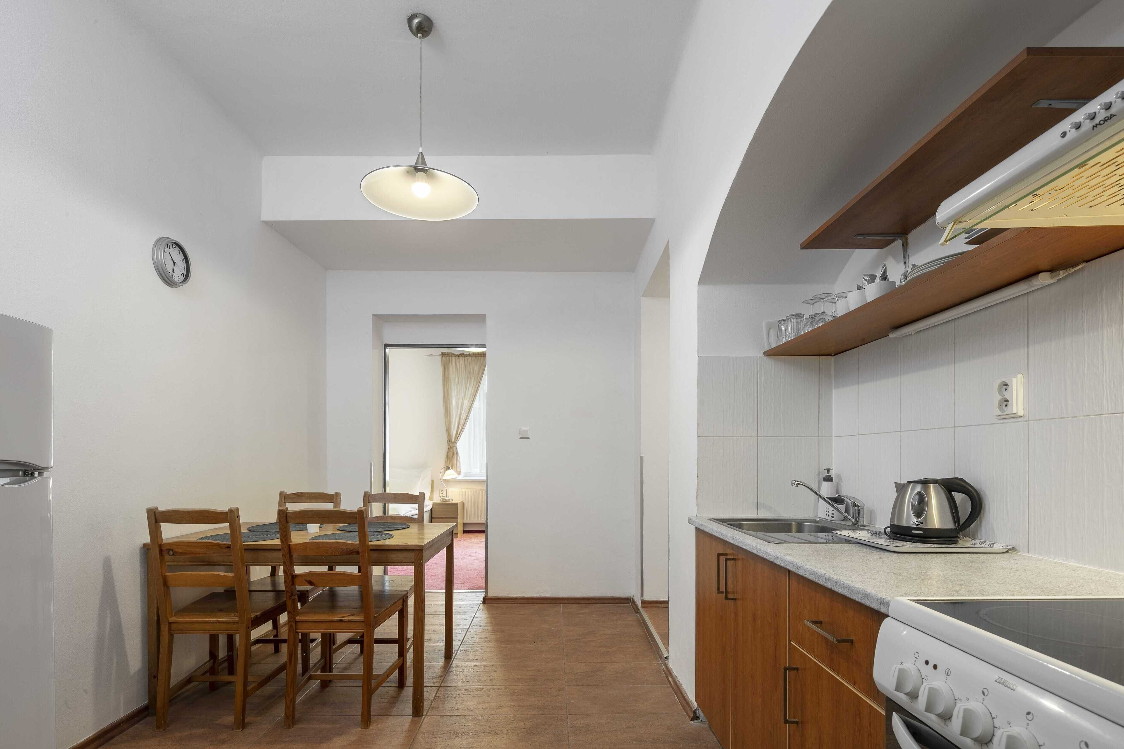A compact kitchen with wooden cabinets, a built-in oven, and a dining area with a table and chairs.
