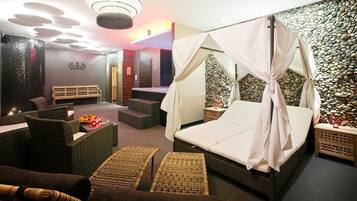 Relax in a serene space with a comfortable bed, wicker seating area, and soothing ambiance.
