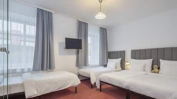 Ein Hotelzimmer mit zwei Einzelbetten, einem an der Wand montierten Fernseher und einem Deckenventilator.