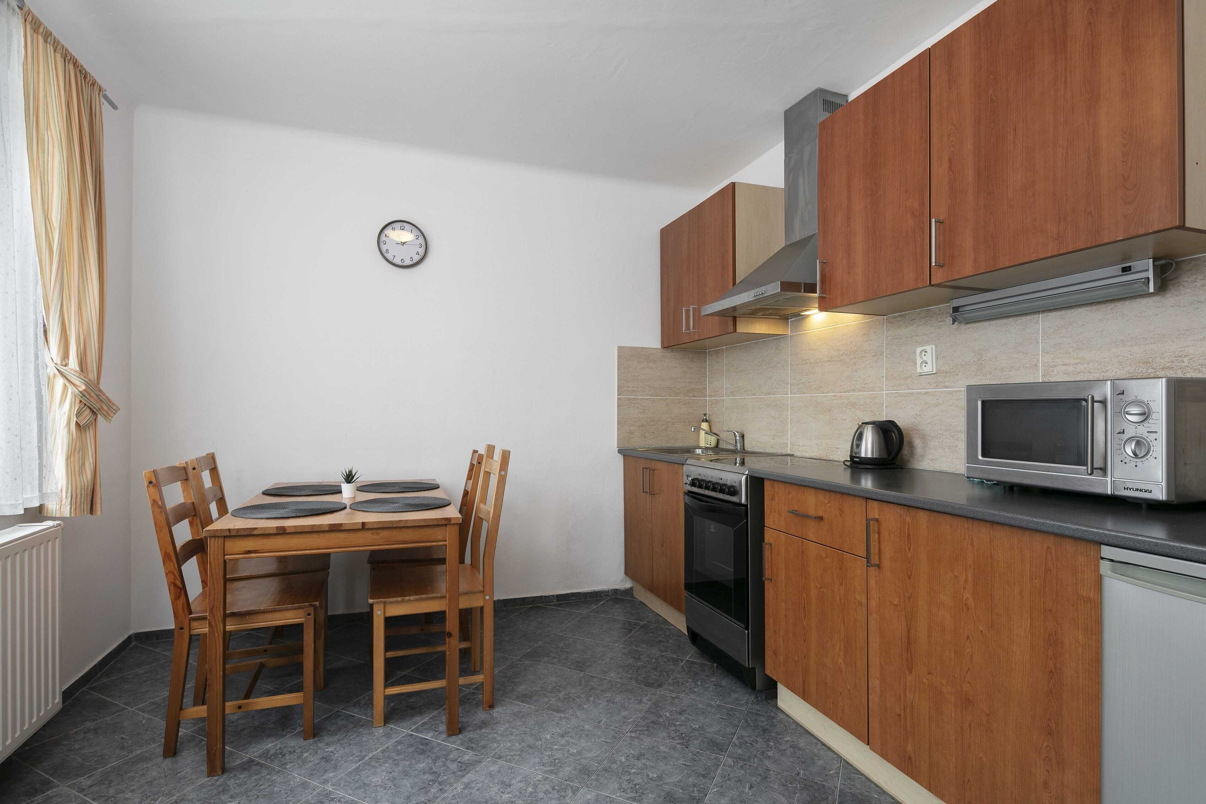 A compact kitchen with wooden cabinets, a microwave, an oven, and a dining table with chairs.