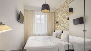 A hotel room with a large bed, two bedside tables, a TV, and a mirror.