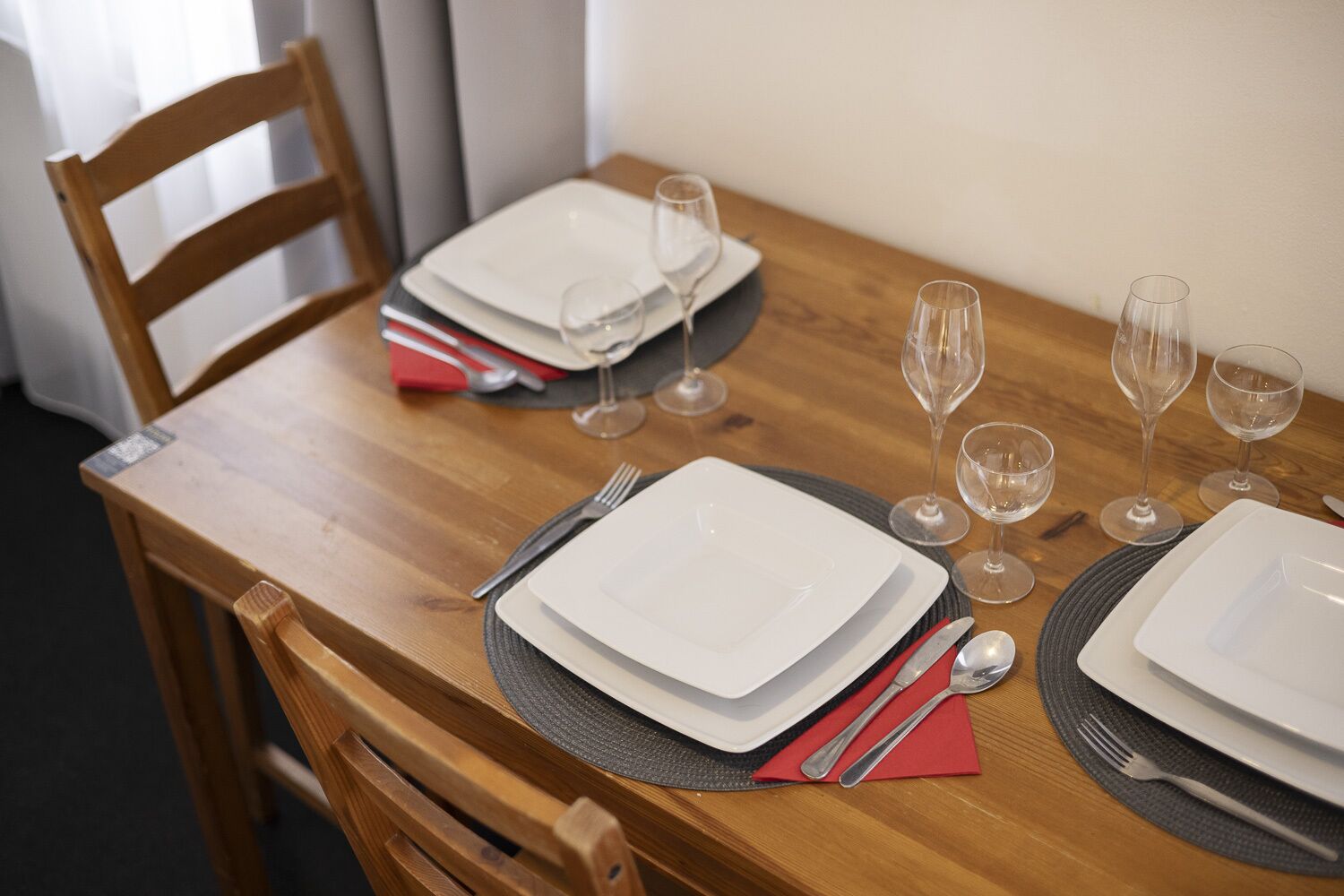 A neatly set dining table with plates, cutlery, and wine glasses.