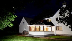 Een huis met twee verdiepingen, een overdekt terras en een gazon.