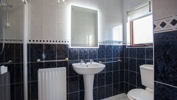 Ein Badezimmer mit einem weißen Standwaschbecken, einer Toilette und einer Duschkabine.