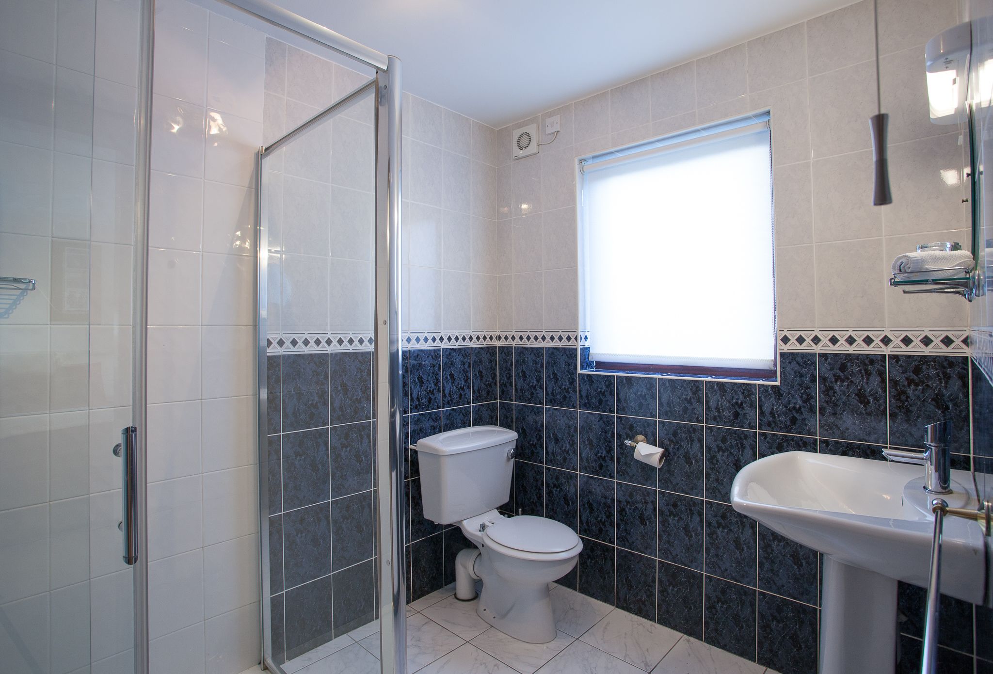 Un baño con cabina de ducha de vidrio, inodoro y lavamanos.