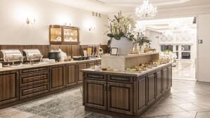 Uma cozinha ampla com armários de madeira, bancada de mármore e uma ilha central com um vaso de flores.