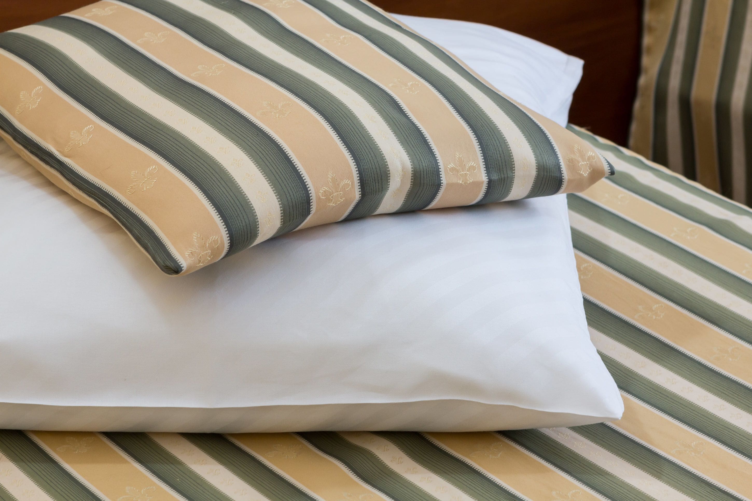 A bed with striped bedding and a pillow with a striped pattern.