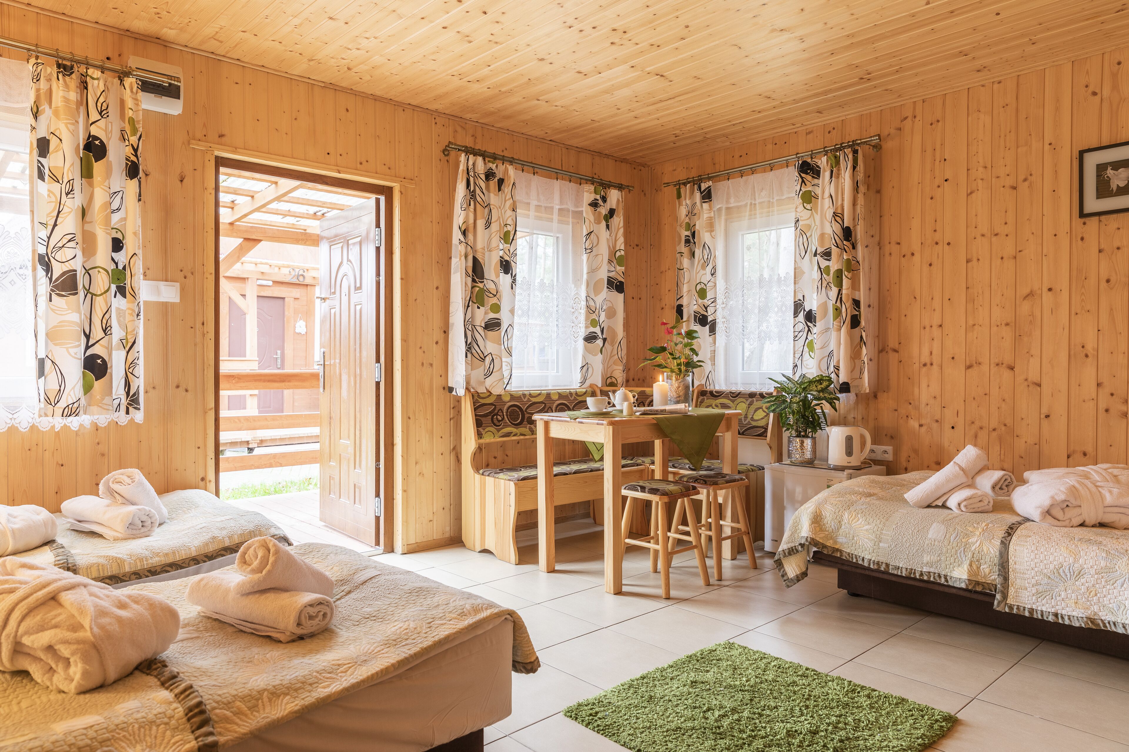 Una cabaña de madera con dos camas, una zona de comedor y un baño.