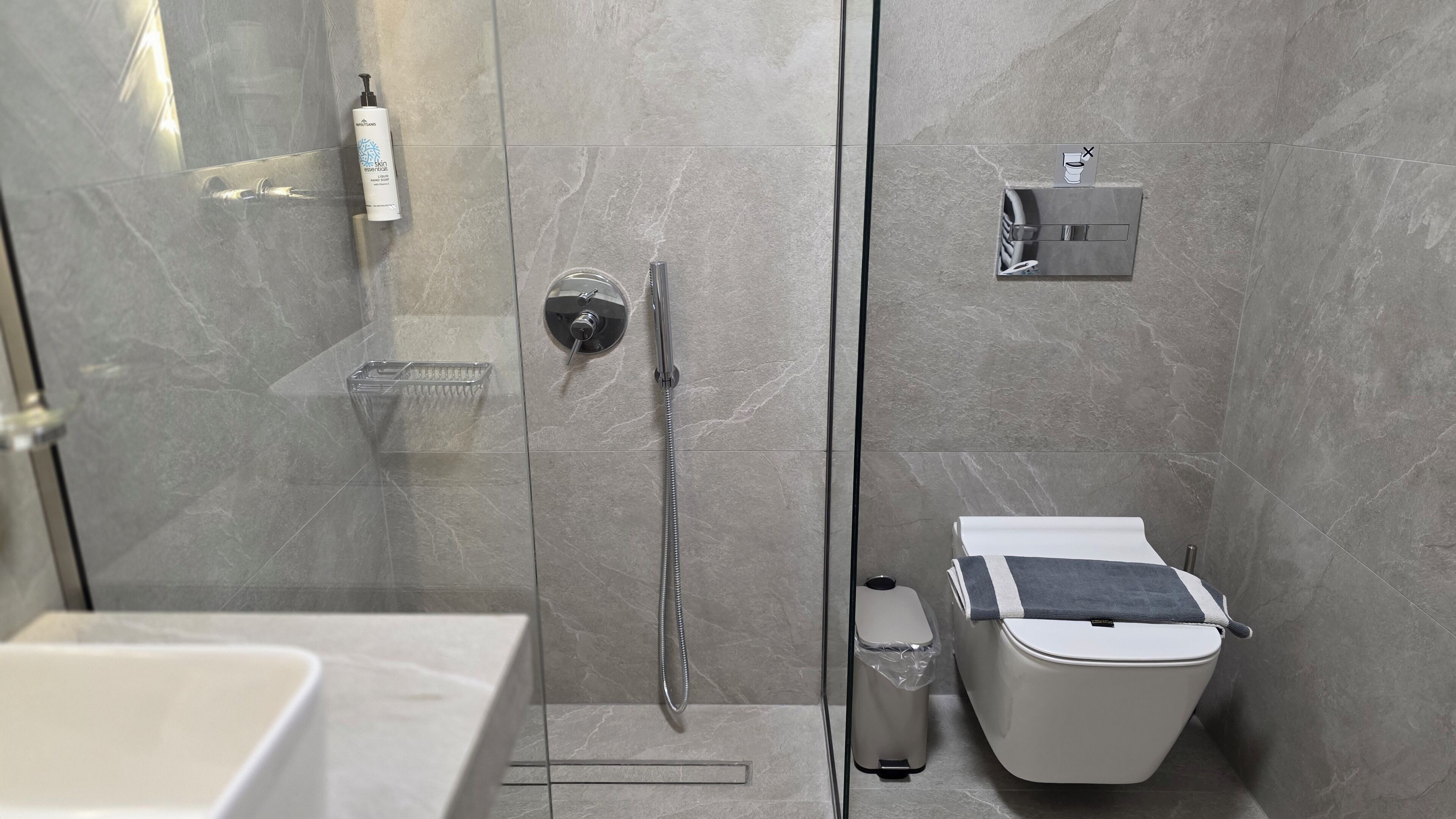 A modern bathroom with a glass-enclosed shower, a toilet, and a sink.