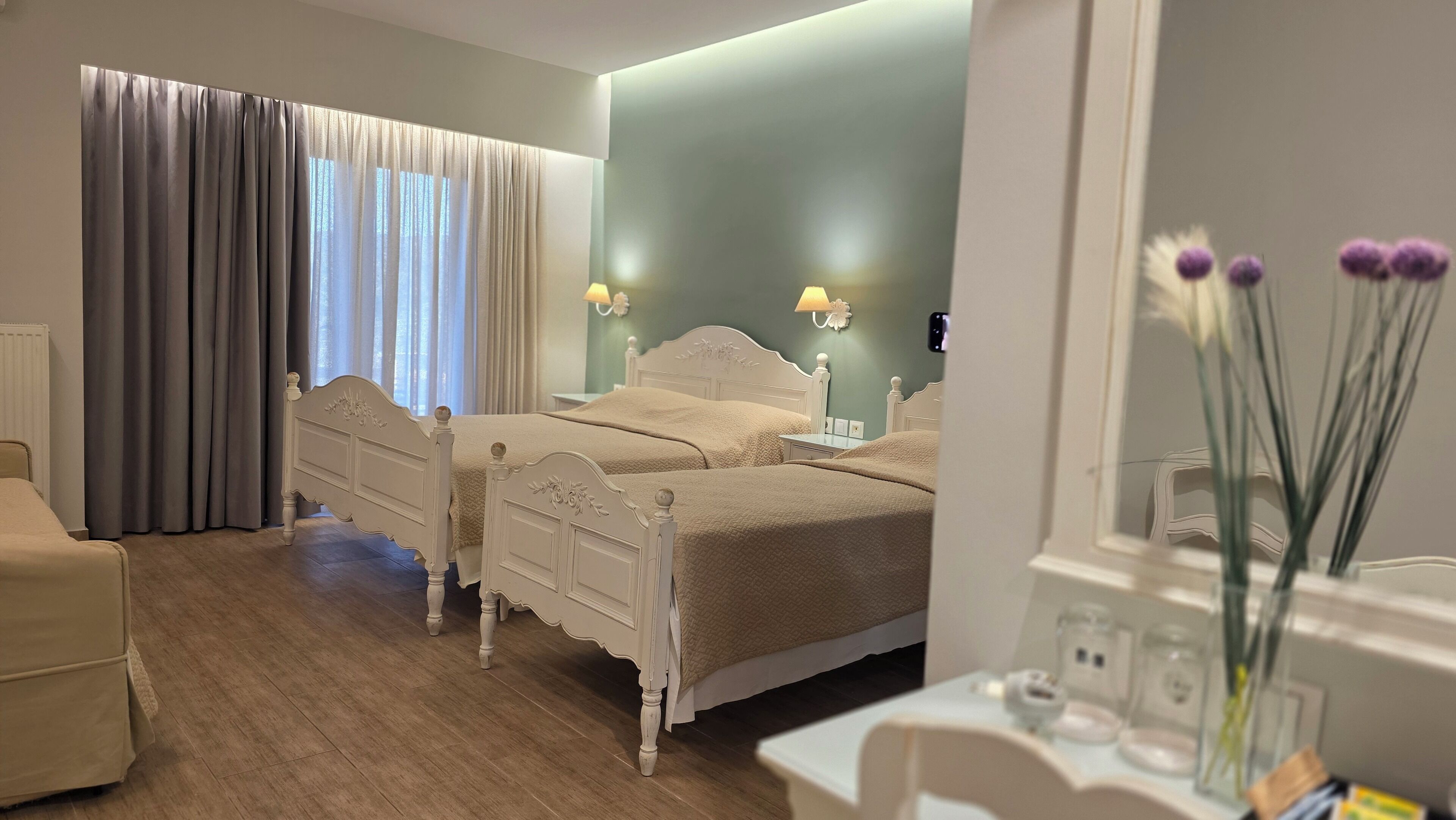 Ein Schlafzimmer mit zwei Betten, einem Nachttisch, einem Sessel und einem Fenster mit Vorhängen.
