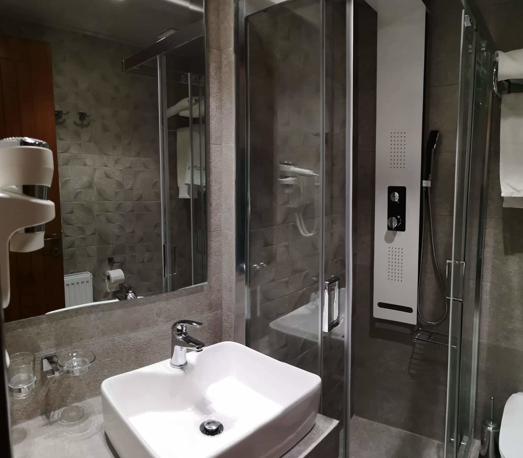 A modern bathroom with a glass-enclosed shower, a white sink, and a mirror.