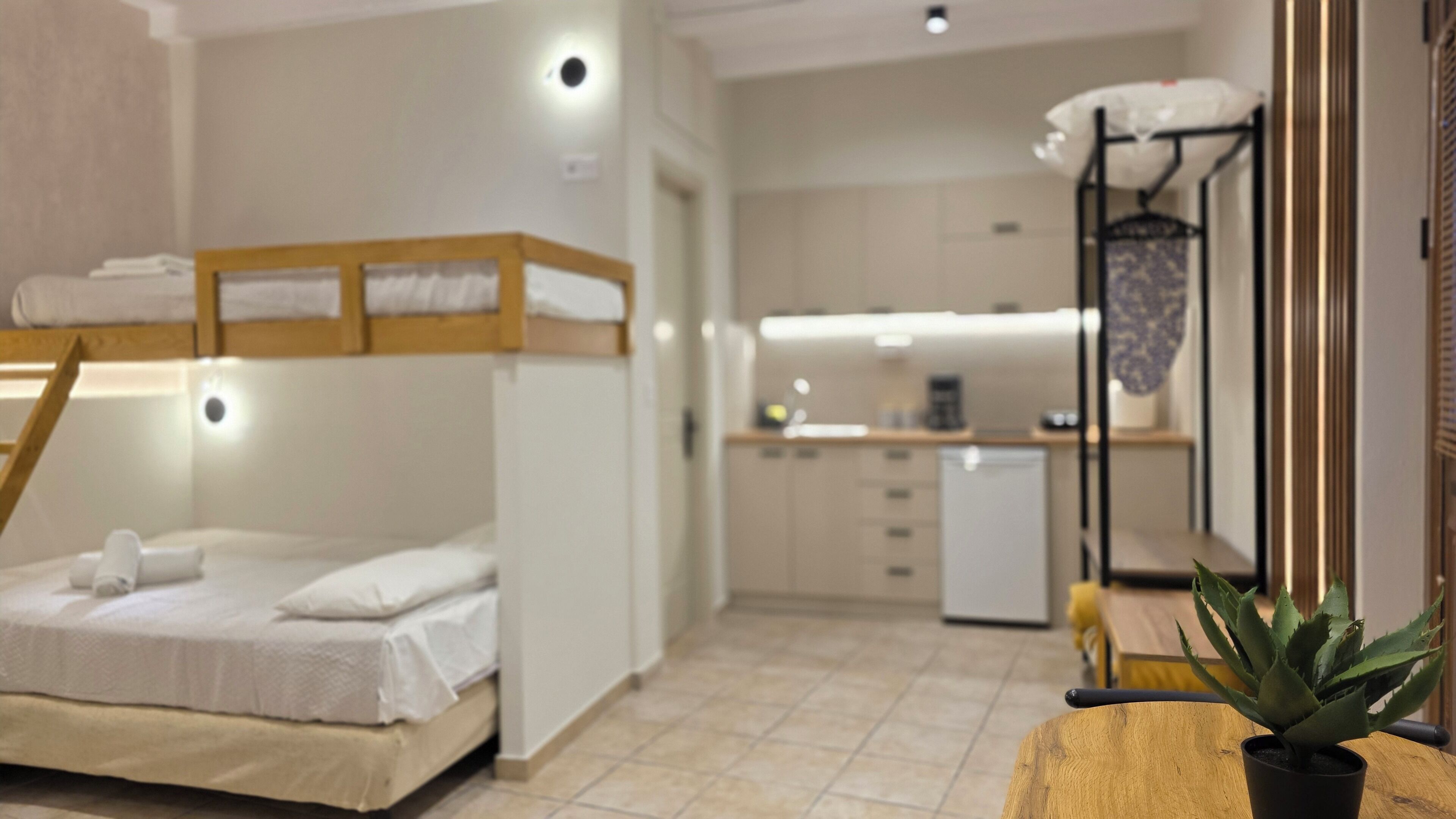 Habitación de hotel compacta con literas, kitchenette y un pequeño comedor.
