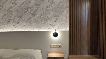 A modern bedroom with a textured wall, a bedside table, and a wooden panel wall.