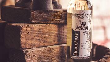 A bottle of Boccus white dry wine placed on a wooden barrel with a vintage press in the background.