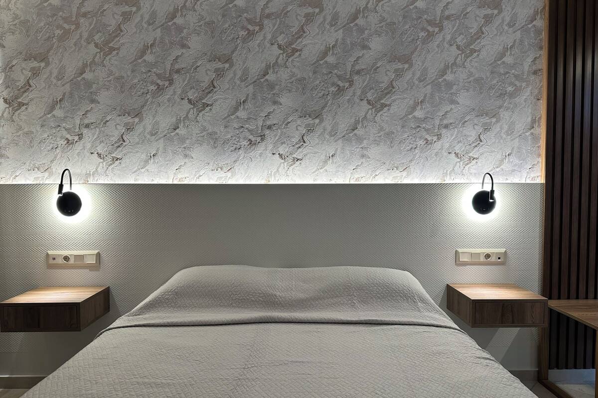 Un dormitorio con una cama grande, dos mesitas de noche e iluminación empotrada.