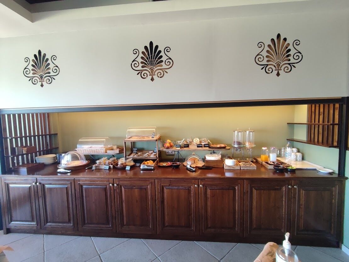 A buffet counter with various food items and beverages, wooden cabinets, and decorative wall elements.