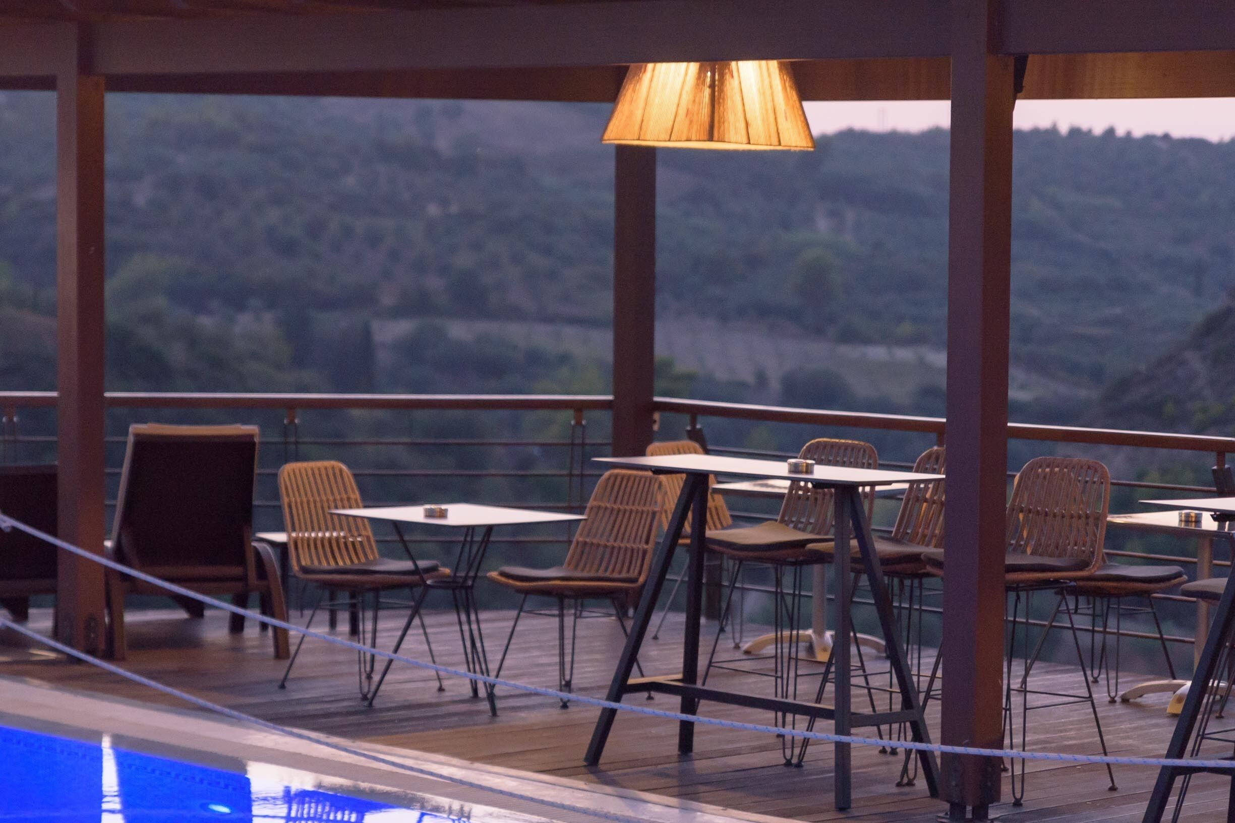 A terrace with tables and chairs, overlooking a hilly landscape.
