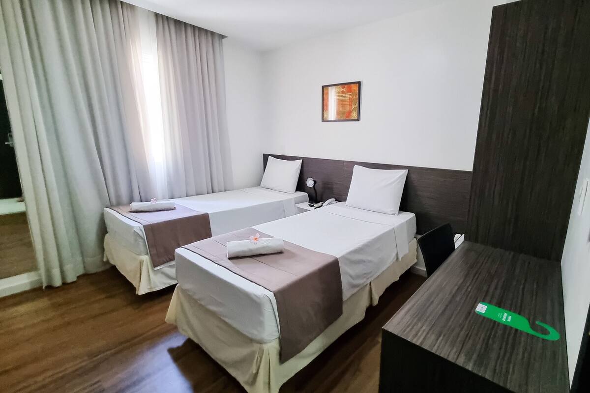 Ein Hotelzimmer mit zwei Betten, einem Schreibtisch und einem großen Spiegel.