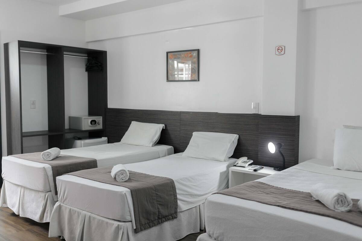 Ein Hotelzimmer mit zwei Betten, einem Nachttisch mit Lampe, einem Telefon und einem Spiegel.