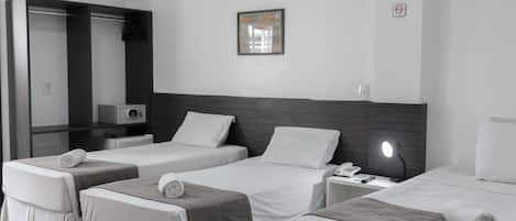 A hotel room with two beds, a bedside table with a lamp, a phone, and a mirror.
