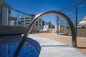 A rooftop pool area with a clear blue sky, a metal pool ladder, and white lounge chairs. - Tropico Praia Hotel (Maceió)