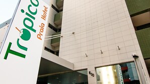 A modern building with a prominent sign for 'Tropico Praia Hotel'.