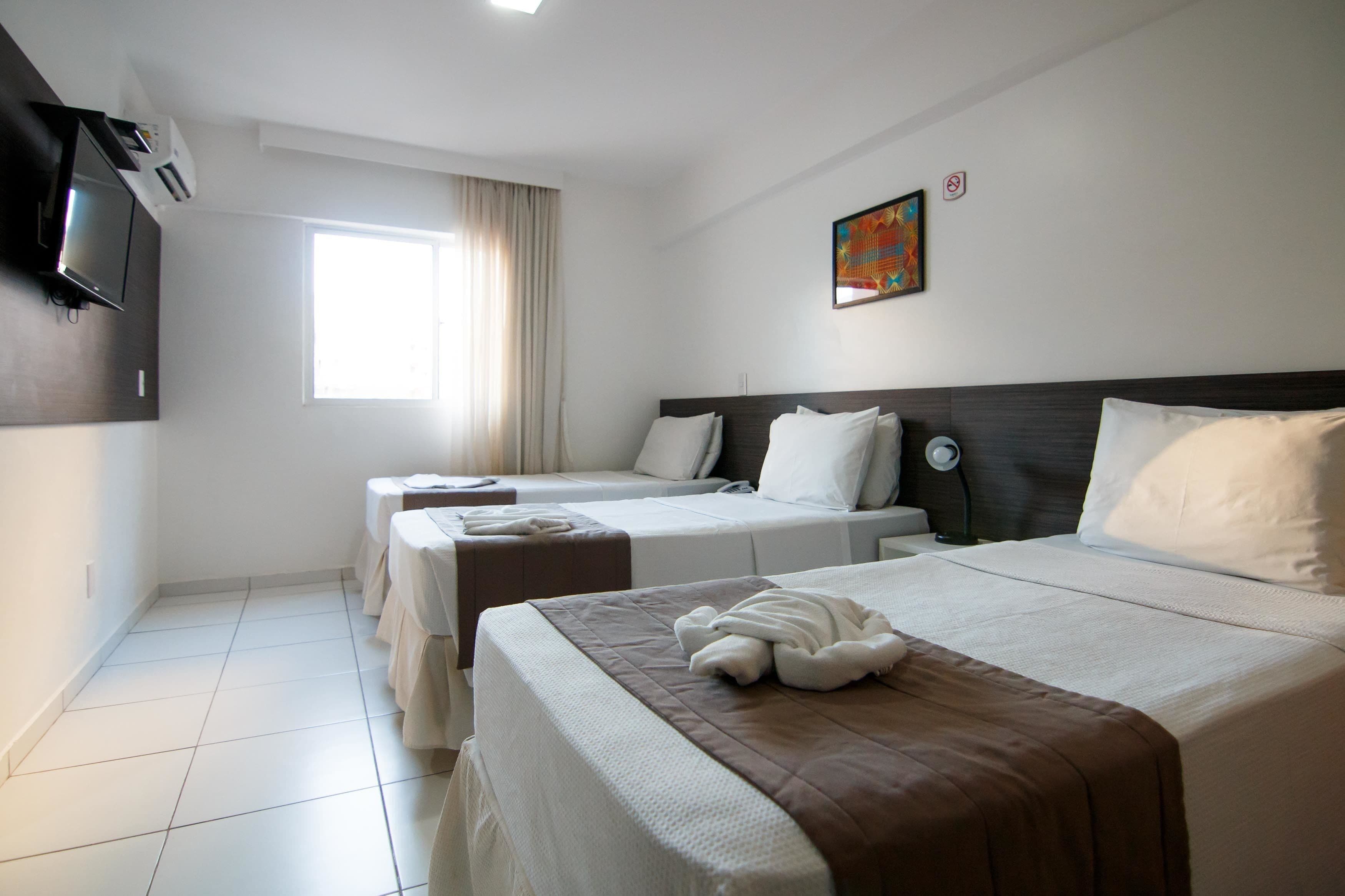 Camera d'albergo con due letti, una televisione e un quadro appeso al muro.