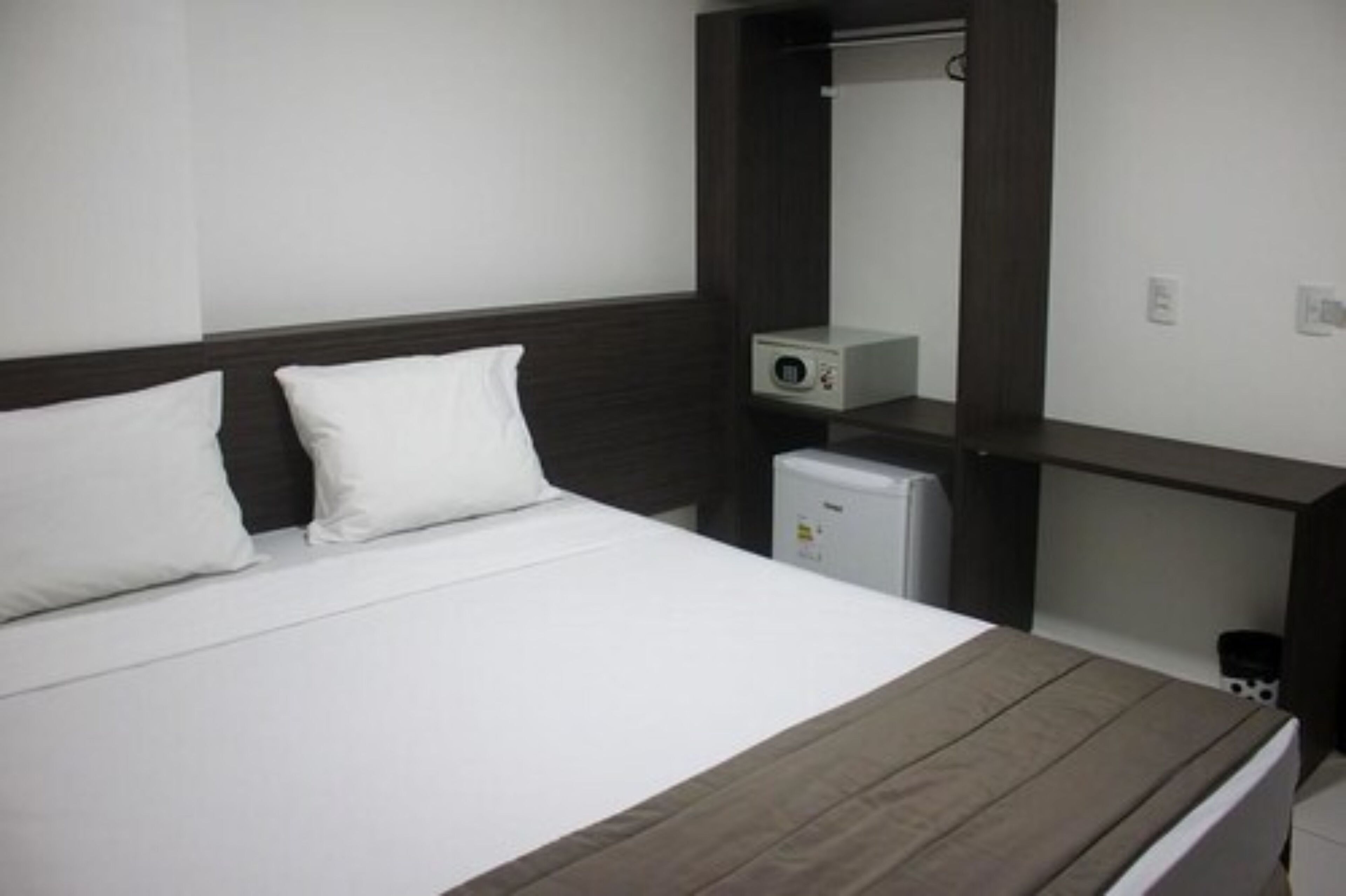 Une chambre d’hôtel avec un lit, un petit bureau, un miroir et un radiateur.